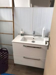 La salle de bains est pourvue d'un lavabo blanc et d'un miroir. dans l'établissement Cottage chaleureux avec jacuzzi, à Saint-François