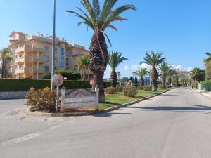 eine Straße mit Palmen und einem Schild und einem Gebäude in der Unterkunft Golf & Playa II in Oliva