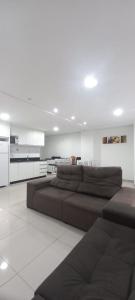 a living room with a large brown couch and a kitchen at Apartamentos Ed London, na Av principal a poucos passos das Termas in Piratuba