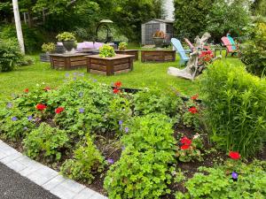 un jardín con flores, mesa y sillas en Gite Chute Couette Cafe, en Notre-Dame-du-Portage