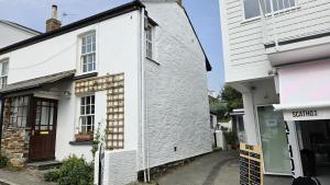 una casa blanca con una ventana en una calle en Hillside Cottage, en Porthscatho