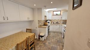 a small kitchen with white cabinets and a table at Hillside Cottage in Porthscatho