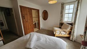 una camera da letto con un letto, una sedia e una finestra di Hillside Cottage a Porthscatho