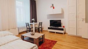 uma sala de estar com um sofá, uma mesa e uma televisão em Flarent Economy Apartments em Viena