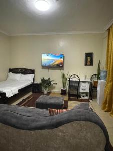 a living room with a bed and a tv on the wall at Zuhura homes in Ruiru