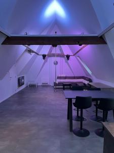 Großes Zimmer mit einem Tisch und violetten Lichtern in der Unterkunft Reiger Burg in Ypern