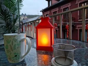 una linterna roja sentada en una mesa junto a una taza en L'Aixotique, en Aix-les-Bains