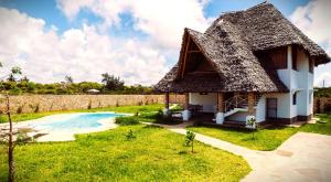 uma casa com telhado de palha e uma piscina em Nyuso za Afrika em Watamu