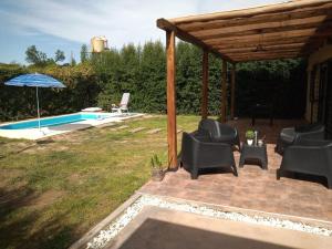 un patio con sillas y una sombrilla junto a la piscina en Casa ROMA en San Rafael