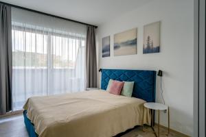 a bedroom with a bed with a blue headboard and a window at Magnolia Sunshine in Budapest