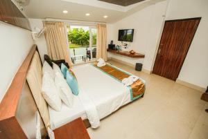 a bedroom with a large bed and a television at Shelter Beach Resort in Mahabalipuram