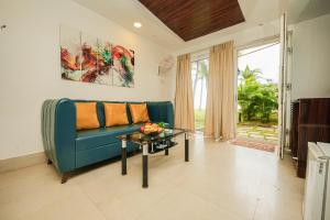 a living room with a blue couch and a table at Shelter Beach Resort in Mahabalipuram