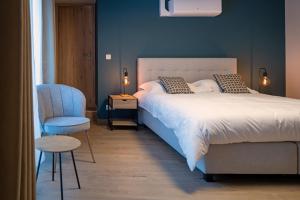 a blue bedroom with a bed and a chair at La table d’Auguste in Dour