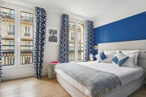 - une chambre avec des rideaux bleus et blancs et un lit dans l'établissement Hotel Elysees Opera, à Paris