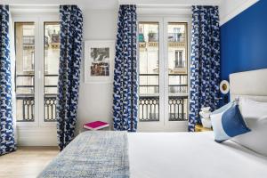 パリにあるホテル エリゼ オペラのベッドルーム(青と白のカーテン、ベッド1台付)