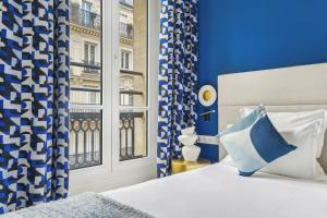 a blue and white bedroom with a bed and a window at Hotel Elysees Opera in Paris