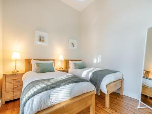 2 camas individuales en una habitación con 2 lámparas en The School Rooms en West Woodburn