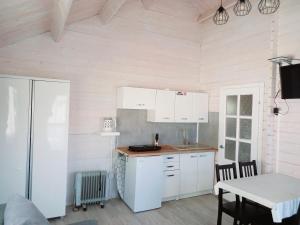 a kitchen with white cabinets and a table at Domki Żeglarz Ustronie Morskie in Ustronie Morskie