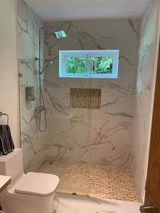 a bathroom with a shower with a toilet and a window at Luxury place playa nueva romana in San Pedro de Macorís
