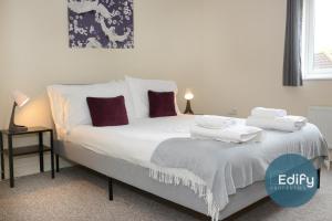 una camera da letto con un letto con lenzuola bianche e cuscini viola di 4 Br 3 Bathroom City Centre Free Parking a Southampton