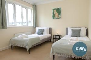 two beds in a room with two windows at 4 Br 3 Bathroom City Centre Free Parking in Southampton