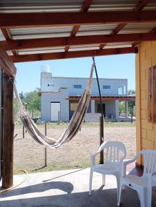 een hangmat op een veranda met 2 stoelen en een gebouw bij Cabaña La Rosita in Villa Quillinzo