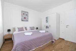 a white bedroom with a large bed with two pillows at Villa Natura Piedra in Slivno +55 photos
