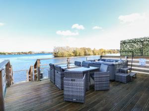 a deck with a table and chairs on the water at Lake View Lodge in Tallington