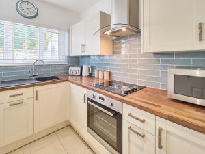 a kitchen with white cabinets and a sink and a microwave at Host & Stay - Grosvenor House in Margate