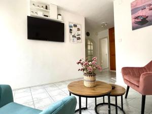 Barát Vendégház - Cosy Guesthouse - Teljes ház privát udvarral - 4 szoba, 2 fürdő في سيجد: غرفة معيشة مع إناء من الزهور على طاولة