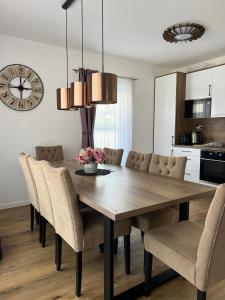 a dining room table with chairs and a clock on the wall at Lipno Village House in Frymburk