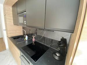 a kitchen with a black counter top with a microwave at Disneyland Dream 6 - Charmant Appartement 8 pax in Montévrain