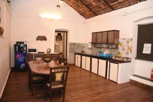 4BHK Private Pool villa in North Goa and Kayaking nearby!! في Moira: مطبخ كبير مع طاولة وثلاجة