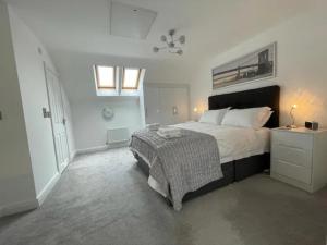 a white bedroom with a bed and a night stand at Sophisticated & Contemporary Modern House for 6 Pass the Keys in Chapel en le Frith