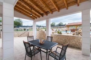 a patio with a table and chairs and a stone wall at Villa Natura Piedra in Slivno