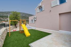 a backyard with a playground with a yellow slide at Villa Natura Piedra in Slivno