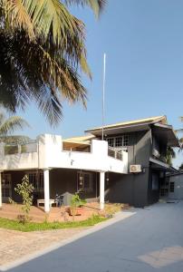 a white building with a palm tree in front of it at Eli Ndatis Self Catering Apartments in Kololi