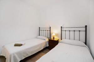 2 letti in una camera con pareti bianche di Apartamento Ribera del Marisco a El Puerto de Santa María