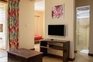 a living room with a flat screen tv and a table at Concha Tropical Flat in Itacaré
