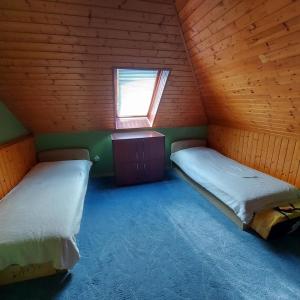 een kamer met 2 bedden in een houten kamer met een raam bij Saci Lak in Gyenesdiás