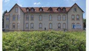 a large tan building with a red roof at Mon Petit Orne Centre thermal Un-Séjour-à-Part in Rombas