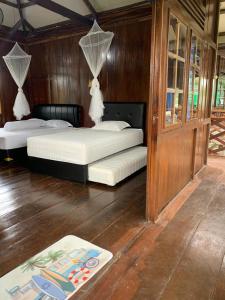 two beds in a room with wooden walls at Arya's Surf Camp in Sukabumi
