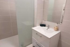 een witte badkamer met een wastafel en een spiegel bij Le p'tit César in Laxou