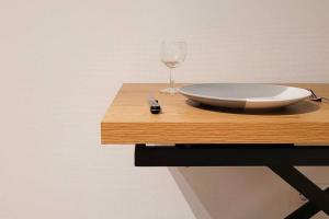 uma mesa de madeira com um prato e um copo de vinho em Le p'tit César em Laxou