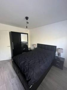 a bedroom with a large black bed in a room at 1-bed apartment w/ electric fireplace in London