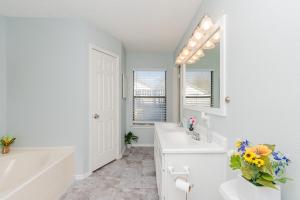 uma casa de banho branca com 2 lavatórios, uma banheira e um espelho. em Superb House By Seaworld, Private Pool & Gameroom em San Antonio