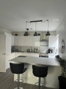 a kitchen with white cabinets and black bar stools at 1-bed apartment w/ electric fireplace in London
