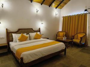 um quarto com uma cama grande e 2 cadeiras em Hidden Trails Ramgarh, Nainital em Rāmgarh