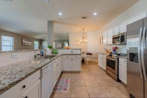 una cocina con armarios blancos y electrodomésticos de acero inoxidable en Luxury Oasis Hot-tub, Games & Bbq By Fiesta Tx en San Antonio