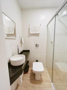 a white bathroom with a toilet and a shower at Babitonga Hostel - 100m da Prainha in São Francisco do Sul